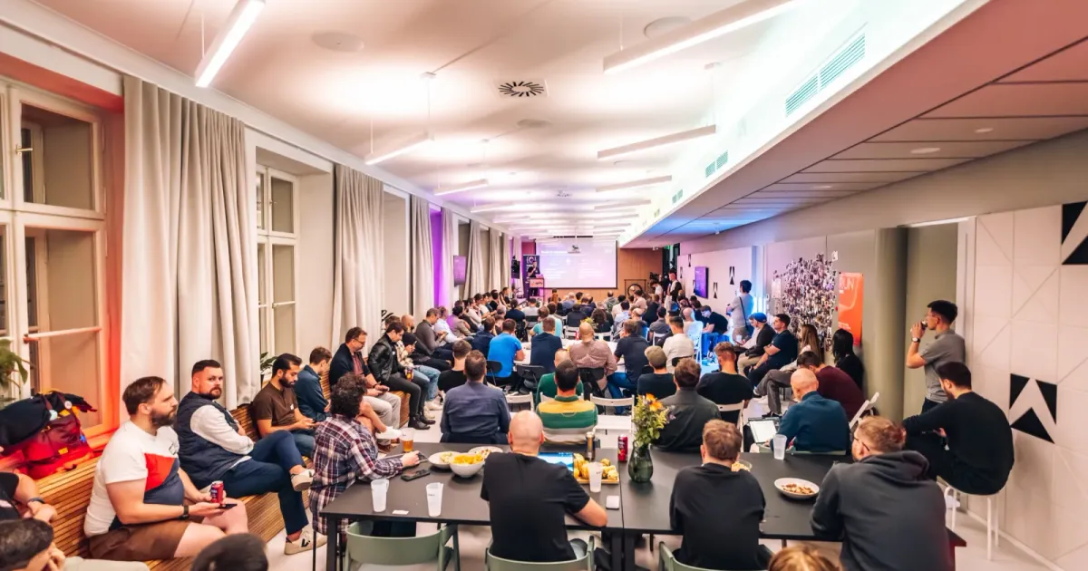 A full room of engineering leaders at ELC meetup #43 in the Apify office in Prague, seated at long tables and on benches, watching a talk on the screen at the far end.