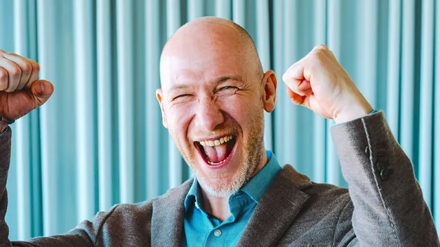 Marian Kamenistak laughing with both fists raised in celebration.