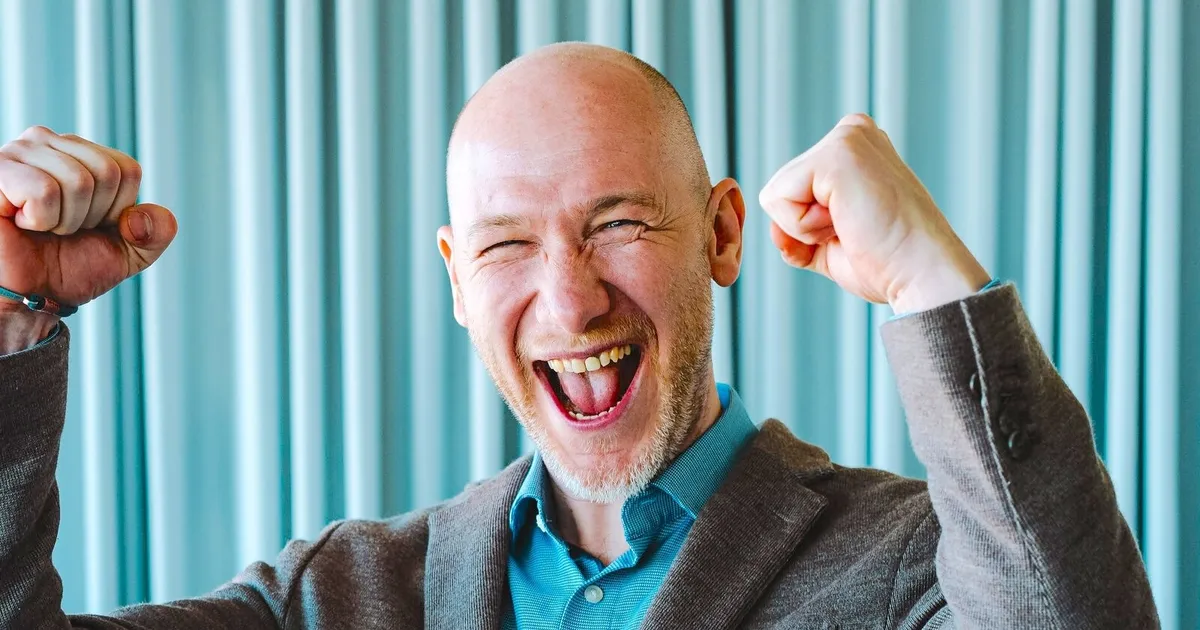 Marian Kamenistak laughing with both fists raised in celebration.