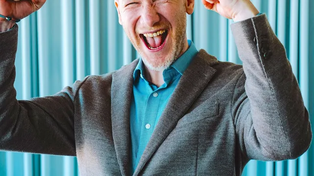 Marian Kamenistak laughing with both fists raised in celebration.
