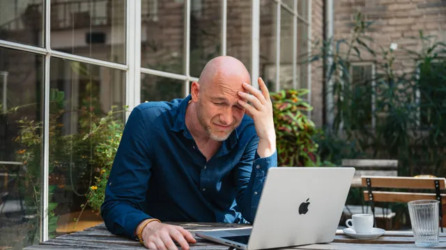 Marian Kamenistak with hand on forehead, looking at his laptop, contemplative.