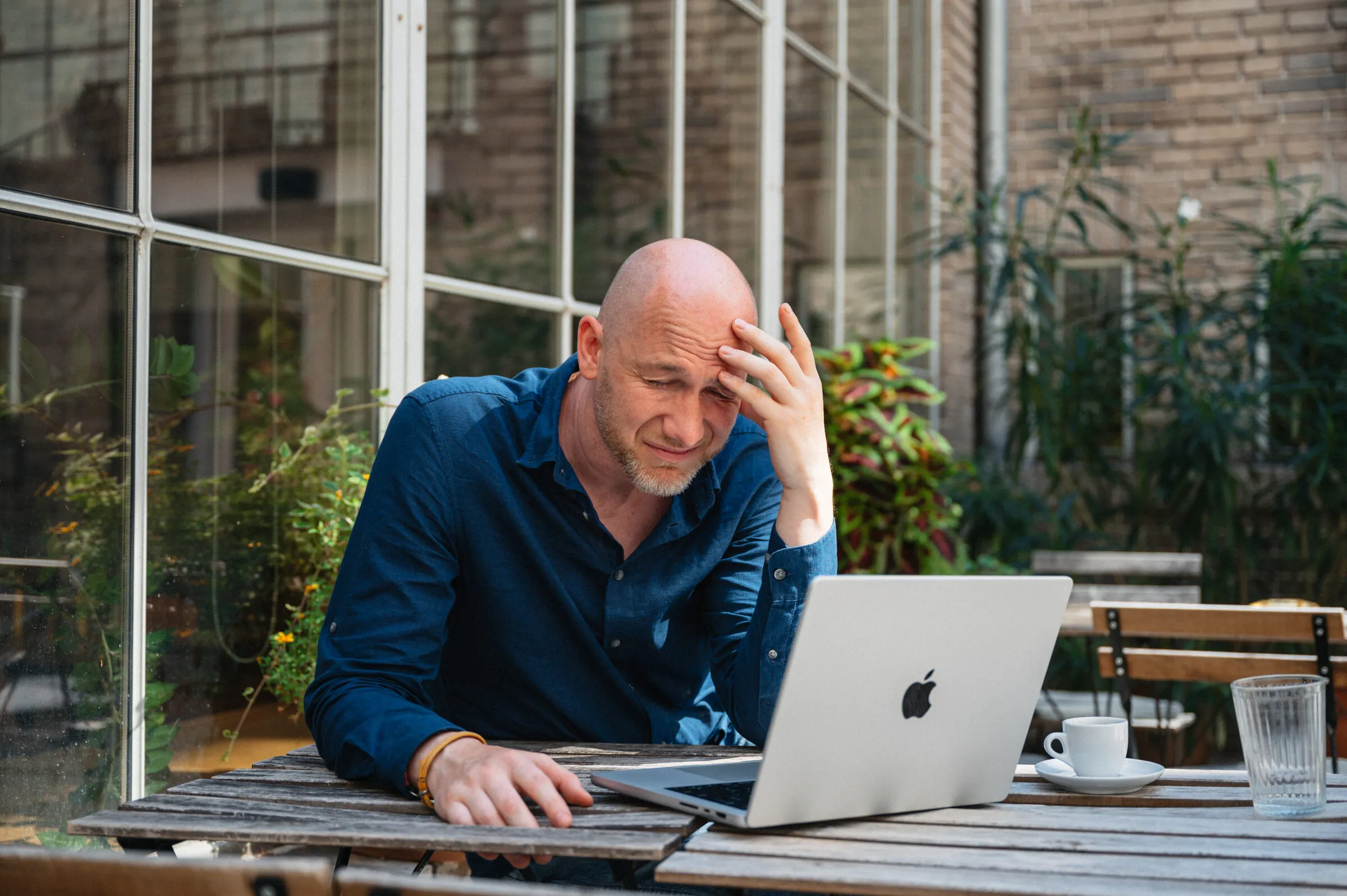 Marian Kamenistak with hand on forehead, looking at his laptop, contemplative.