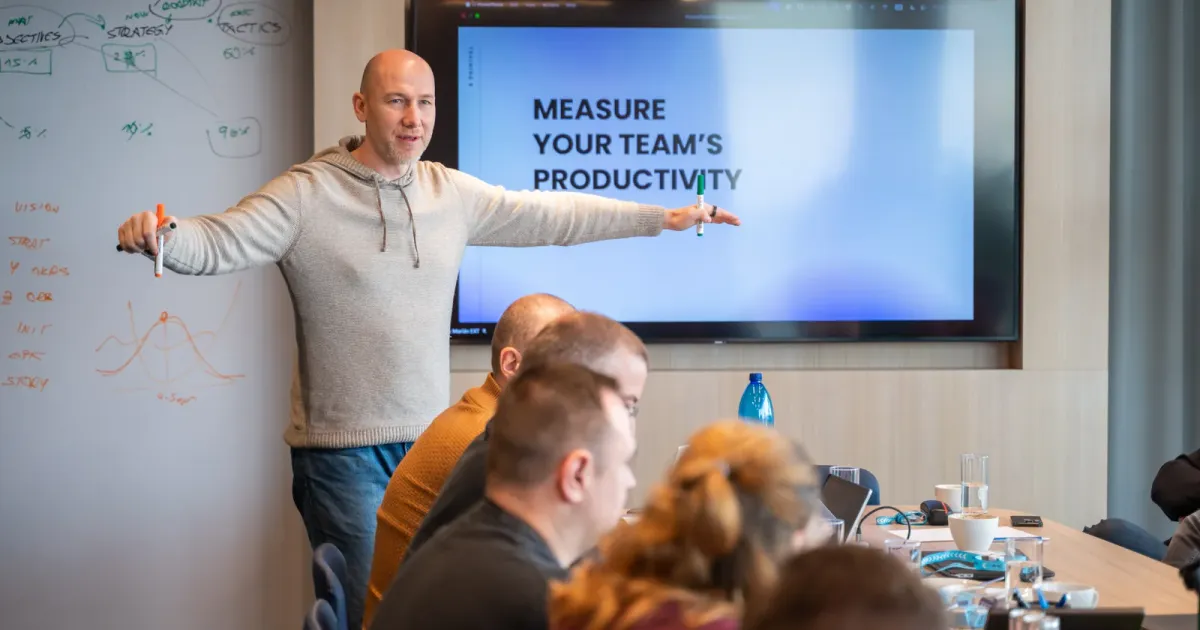 Marian Kamenistak vede workshop před obrazovkou s nápisem „Změř produktivitu svého týmu“, na tabuli poznámky ke strategii.