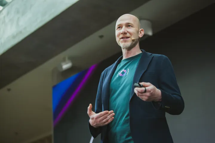 Marian Kamenistak speaking with a headset mic at the Engineering Leaders Conference, clicker in hand mid-gesture.