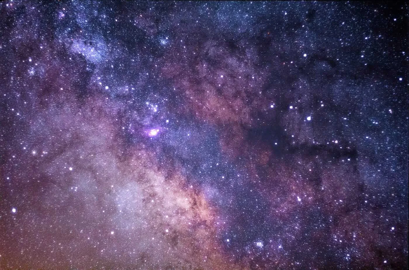 The Milky Way spread across a night sky, dense with purple and blue stars