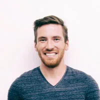 Headshot of a smiling course participant in a navy v-neck against a plain white wall