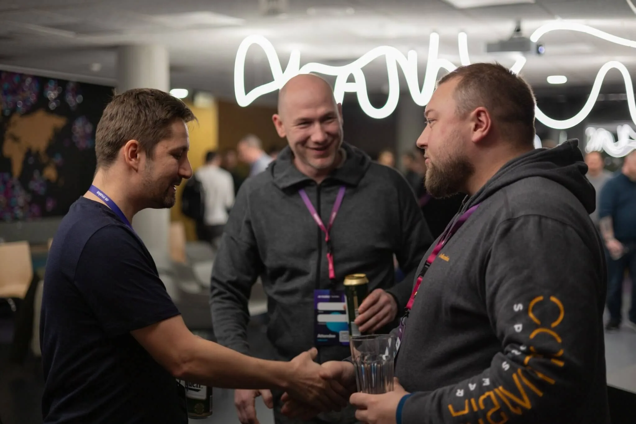 Tři muži si podávají ruce a povídají si u piva na networkingovém večeru pro IT manažery