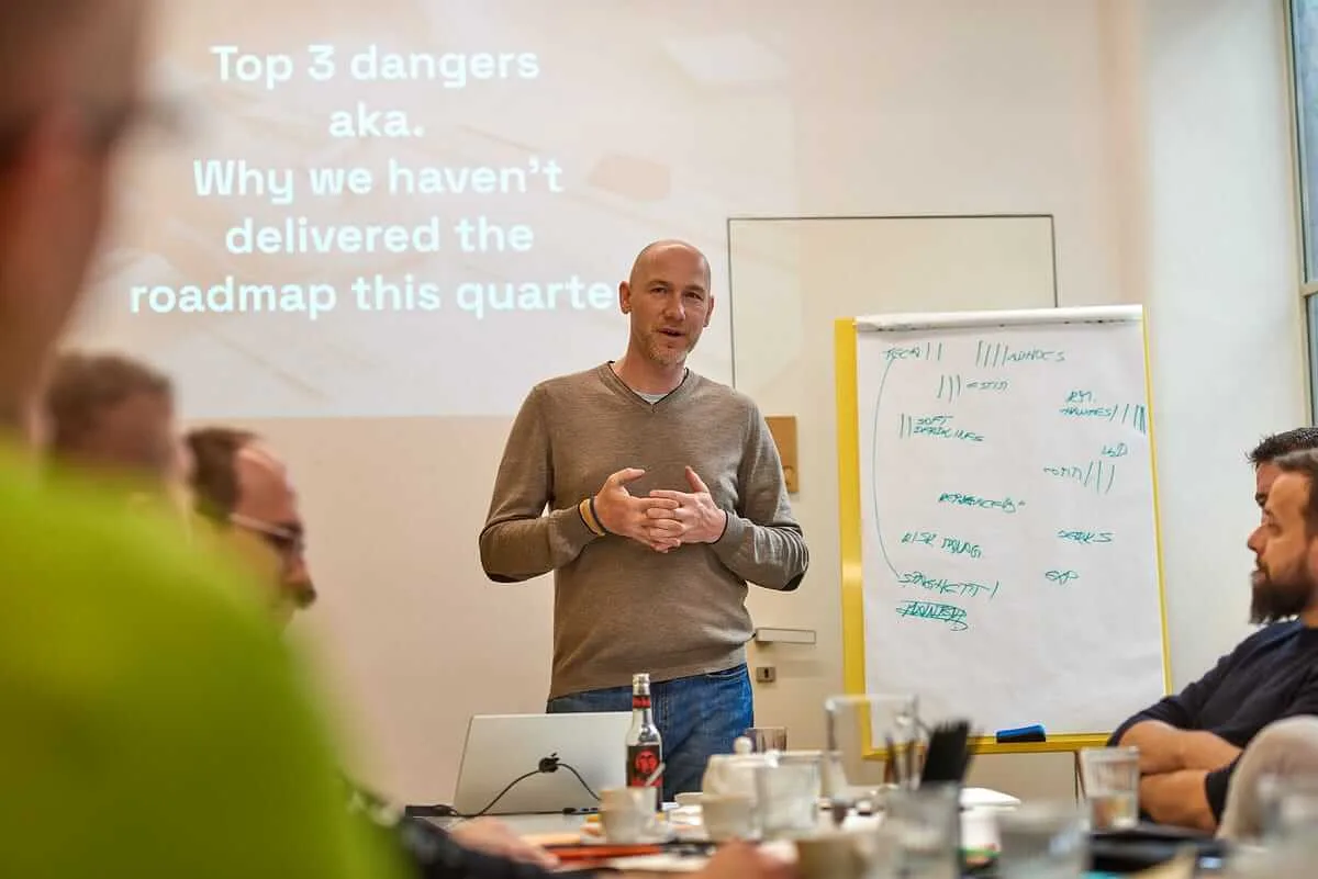Marian Kamenistak leading an on-site workshop, slide reads Top 3 dangers: why we haven't delivered the roadmap