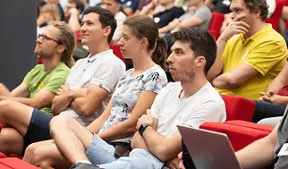 Row of engineering leaders in red conference seats, listening closely to a talk at an ELC meetup