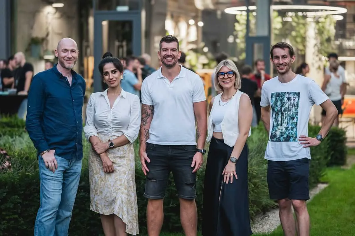 Marian Kamenistak with four community organisers at an outdoor evening event in a courtyard garden