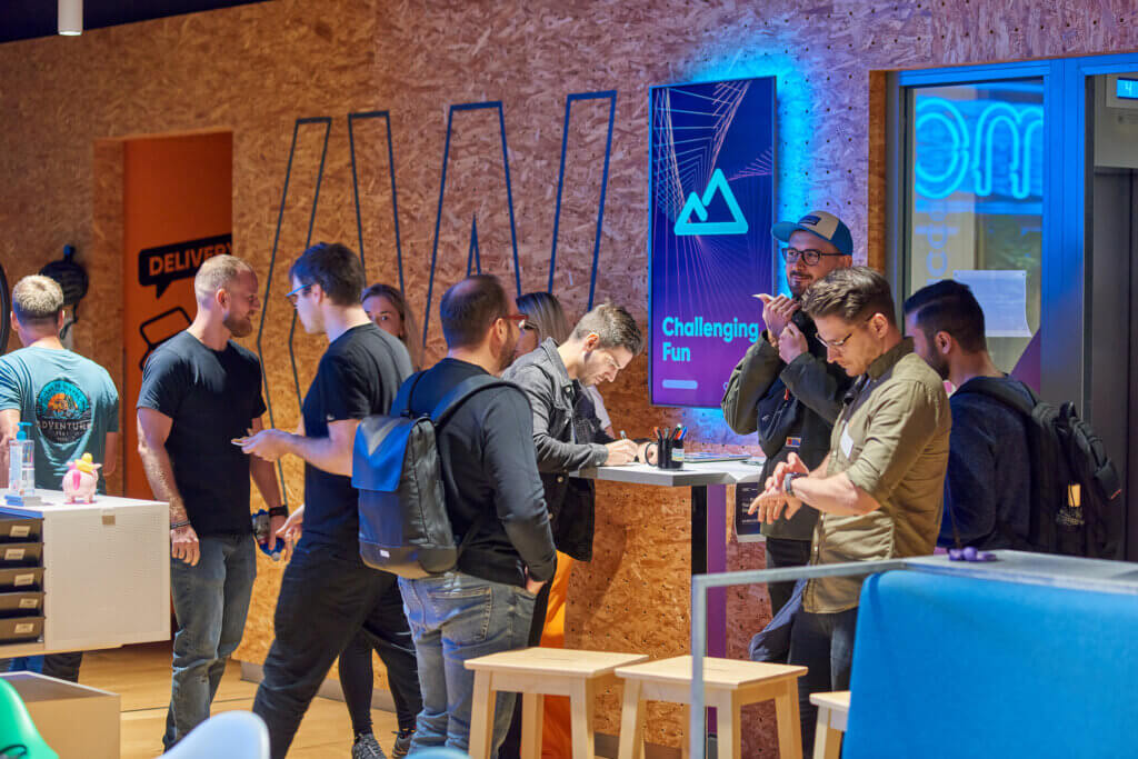 Group of people standing around a table, engaged in a discussion or collaborative activity during a community of practice meeting.