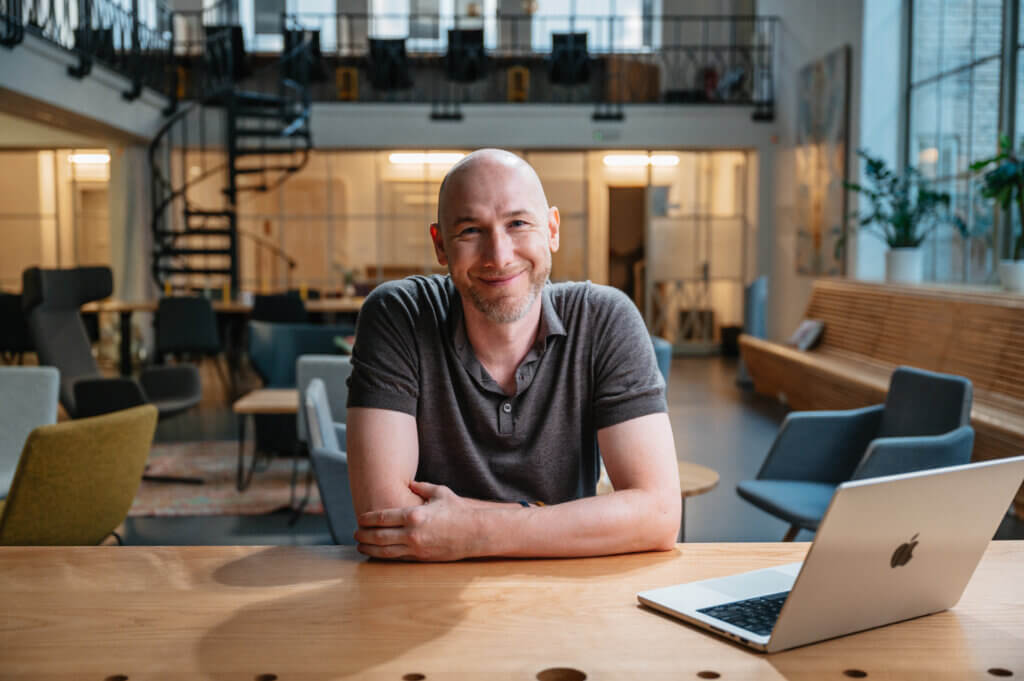 Marian sitting at a desk, smiling while working on his computer.